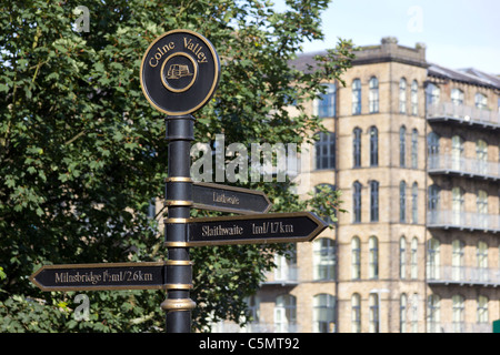 Un panneau de la Colne Valley sur l'Huddersfield canal étroit ; Titanic Mill Linthwaite flou en arrière-plan Banque D'Images