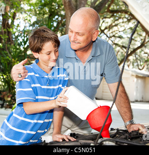 Le père enseigne à son fils comment mettre l'huile dans la voiture familiale. Banque D'Images