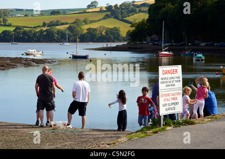 Les enfants en crabe du barrage pour un raz de mill pond, à Stoke Gabriel sur la rivière Dart sans tenir compte des avis de sécurité Banque D'Images