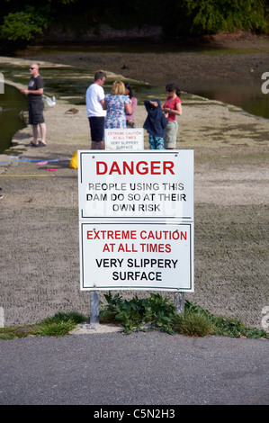 Les enfants en crabe du barrage pour un raz de mill pond, à Stoke Gabriel sur la rivière Dart sans tenir compte des avis de sécurité Banque D'Images