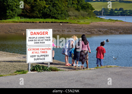 Les enfants en crabe du barrage pour un raz de mill pond, à Stoke Gabriel sur la rivière Dart sans tenir compte des avis de sécurité Banque D'Images