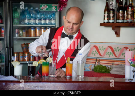 Cuba, Trinidad. Barman au travail. Le rouge, jaune et vert verre est appelé un Trinidad Colonial. Banque D'Images