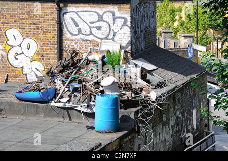 L'Est de Londres et de décharge junk horreur des barbelés sur un toit plat avec graffiti peint sur mur d'Hackney Wick Royaume-uni Angleterre Londres East End Banque D'Images