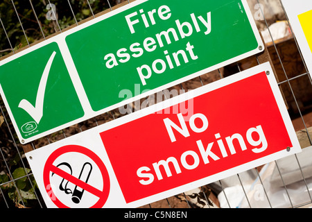 Un livre vert et blanc point de rassemblement incendie sign, rouge et blanc aucun signe de fumer sur un chantier England UK Banque D'Images