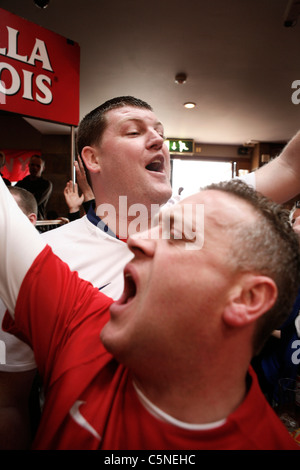 Manchester Utd unofficial compositeur Peter Boyle conduisant le chant de Manchester Utd fans à l'Évêque Blaize Pub. Banque D'Images