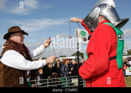 Deux hommes jouer conkers, l'un portant un casque de chevalier, lors du championnat de conker, dans la région de Castel Guelfo di Bologna, Northamptonshire Banque D'Images