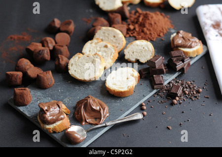 Tranches de baguette avec la crème au chocolat, morceaux de chocolat et truffes, poudre d'cokoa Banque D'Images