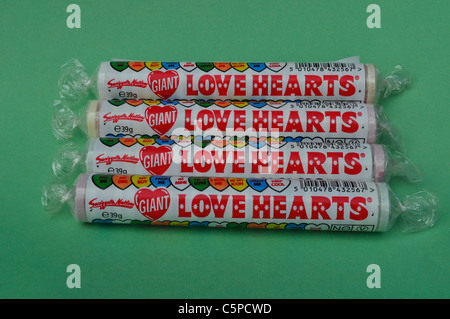 Quatre Love Heart Sweet Candy les paquets sur un fond vert. Banque D'Images