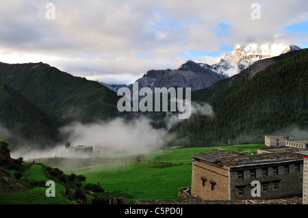 Matin brouillard recouvre Yading village. Xiannairi en arrière-plan. Daocheng Yading Nature Reserve, Sichuan, Chine. Banque D'Images