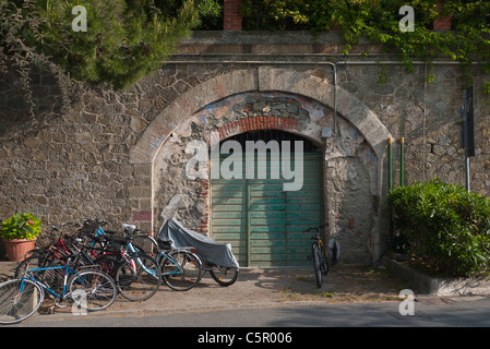 Un grand portail vert avec un béton et brique arch est encastré dans un mur de pierre avec des bicyclettes devant Monterosso, Cinque Terre, Italie Banque D'Images