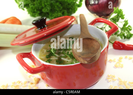 Soupe à l'alphabet avec carottes, poireaux, oignons et le persil dans un pot rouge Banque D'Images