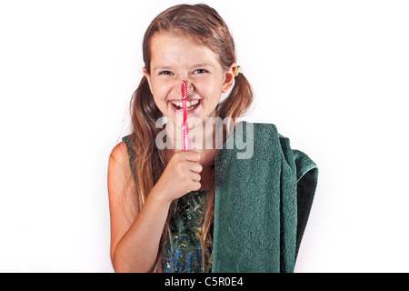 Fillette de huit ans avec une brosse à dents et une serviette pour nettoyer les dents Banque D'Images