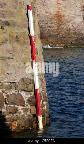 Mesurer la profondeur de l'eau sur le mur de Braye Harbour. Alderney, Channel Islands, Royaume-Uni Banque D'Images