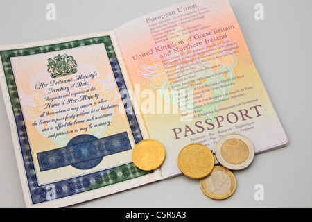 Le Royaume-Uni, la Grande-Bretagne. Un passeport britannique ouvrir avec quelques pièces en euro pour voyager dans la zone euro Banque D'Images