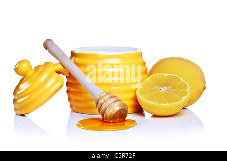 Photo d'un pot de miel en forme de ruche avec citron et balancier isolé sur un fond blanc. Banque D'Images