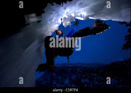 L'escalade sur glace en nocturne sur le bord d'une grotte. Banque D'Images