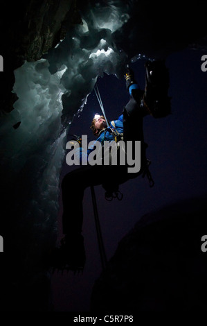 L'escalade sur glace en nocturne sur le bord d'une grotte. Banque D'Images