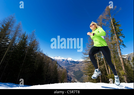 Une femme courir dans les montagnes enneigées. Banque D'Images