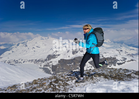 Grimpeur sur glace dans la grotte avec vue sur la montagne derrière. Banque D'Images