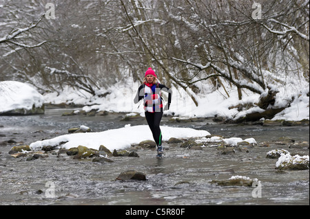 Un jogger traversant une rivière de neige. Banque D'Images