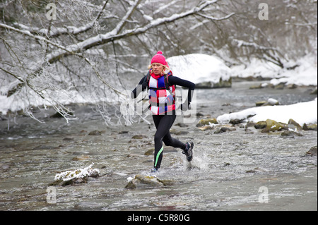 Un jogger traversant une rivière de neige d'hiver. Banque D'Images