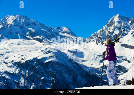 Un skieur donne sur une vue imprenable des montagnes enneigées en hiver. Banque D'Images