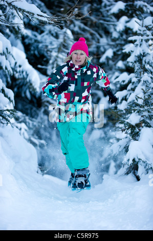 Une femme en raquettes à travers une forêt enneigée. Banque D'Images