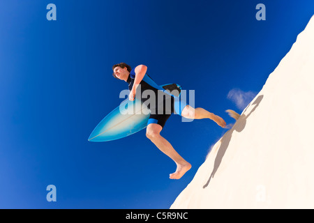 Surfer à travers les dunes de sable de la mer. Banque D'Images