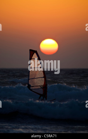 Une planche à voile à l'état de la mer au coucher du soleil. Banque D'Images