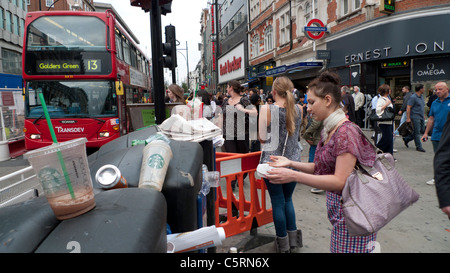 Un groupe d'acheteurs en attente de bus pour traverser la rue Oxford occupé près de déchets plastiques dans la poubelle près de Bond Street London UK KATHY DEWITT Banque D'Images