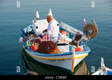 Un vieil homme rss goélands jaune sur un bateau de pêche traditionnel grec de Skala Eresou, Lesbos, Grèce. Banque D'Images