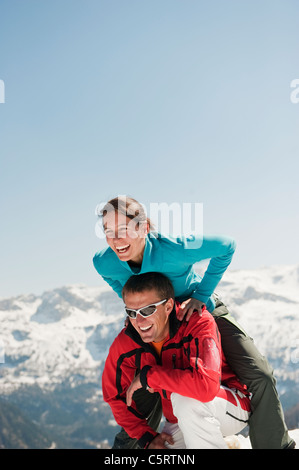 L'Autriche, Pays de Salzbourg, Altenmarkt-Zauchensee, Mid adult woman sautant au-dessus de l'homme en hiver Banque D'Images