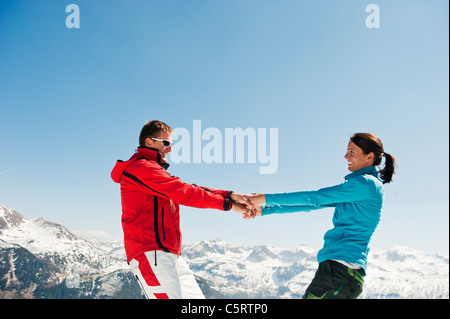 L'Autriche, Pays de Salzbourg, Altenmarkt-Zauchensee, Mid adult couple holding hands and spinning en hiver Banque D'Images