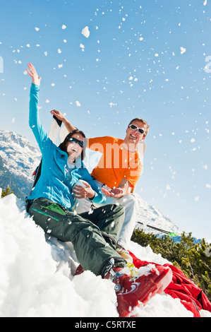 L'Autriche, Pays de Salzbourg, Altenmarkt-Zauchensee, Mid adult couple assis dans la neige et s'amuser Banque D'Images