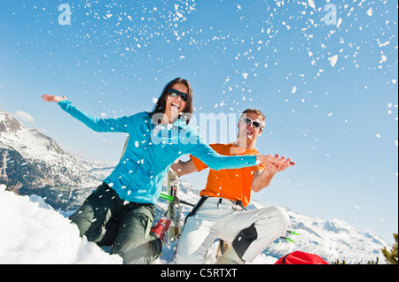 L'Autriche, Pays de Salzbourg, Altenmarkt-Zauchensee, Mid adult couple assis dans la neige et s'amuser Banque D'Images