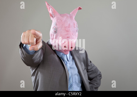 Close up of businessman avec des porcs tête qui pointe à l'office contre fond gris Banque D'Images