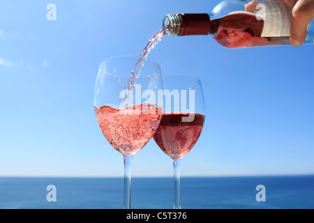 Verser le vin rosé par l'océan. Banque D'Images