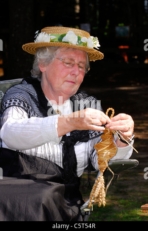 Femme âgée en costume victorien au dimanche rustique faisant un tas de maïs, Rural Life Centre, Tilford, près de Farnham, Surrey,ROYAUME-UNI. Banque D'Images