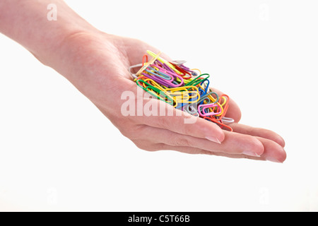 Close up of woman's hand holding paper clips against white background Banque D'Images