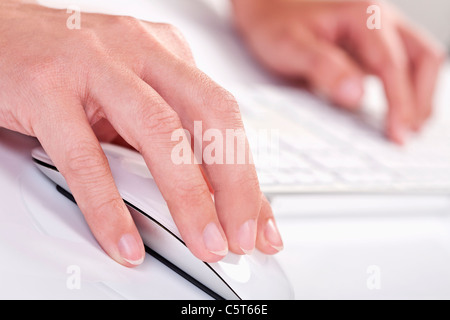 Close up of woman's hand holding de la souris et de l'écriture sur clavier Banque D'Images