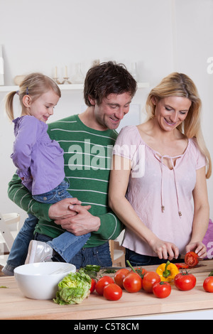 Germany, Bavaria, Munich, mère de préparer la salade avec le père et la fille debout à côté de sa Banque D'Images