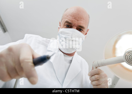 Germany, Bavaria, Landsberg, dentiste wearing mask holding équipement médical, Banque D'Images