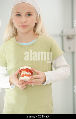 Germany, Bavaria, Landsberg, Girl (8-9) holding model de dents, portrait Banque D'Images