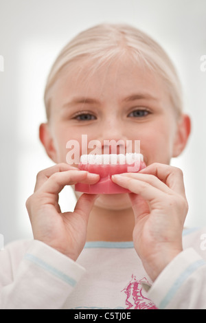 Germany, Bavaria, Landsberg, Girl (8-9) holding model de dents, portrait Banque D'Images