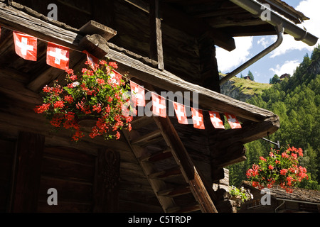 La Suisse, Alpes valaisannes, Val d'Herens, Les Hauderes, Log Cabin décorées avec des bannerets Suisse Banque D'Images