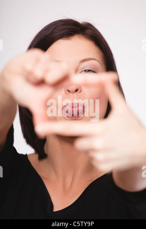 Close up of mid adult woman showing hand sign against white background, portrait Banque D'Images