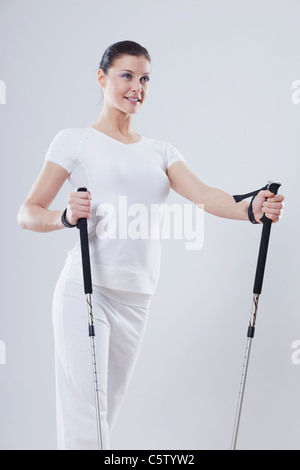 Mid adult woman avec bâtons de ski contre fond blanc Banque D'Images
