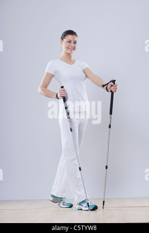 Mid adult woman avec bâtons de ski against white background, smiling, portrait Banque D'Images