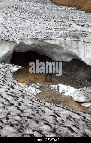 Randonneur à dans l'entrée d'une grotte de glace s'est effondrée sur le sentier de randonnée Laugavegur Islande Banque D'Images