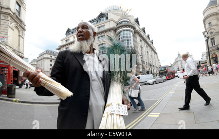 Londres, Angleterre, Royaume-Uni. L'homme musulman de plume de paon vente sur Coventry Street / Piccadilly Circus Banque D'Images